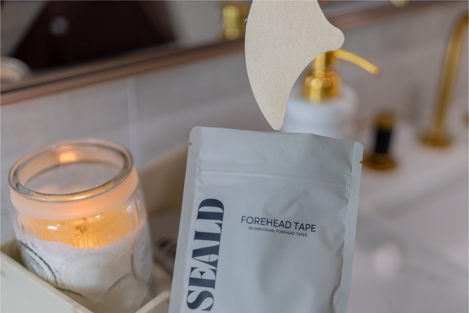 SEALD forehead tape package on a bathroom counter with a lit candle and mirror in the background
